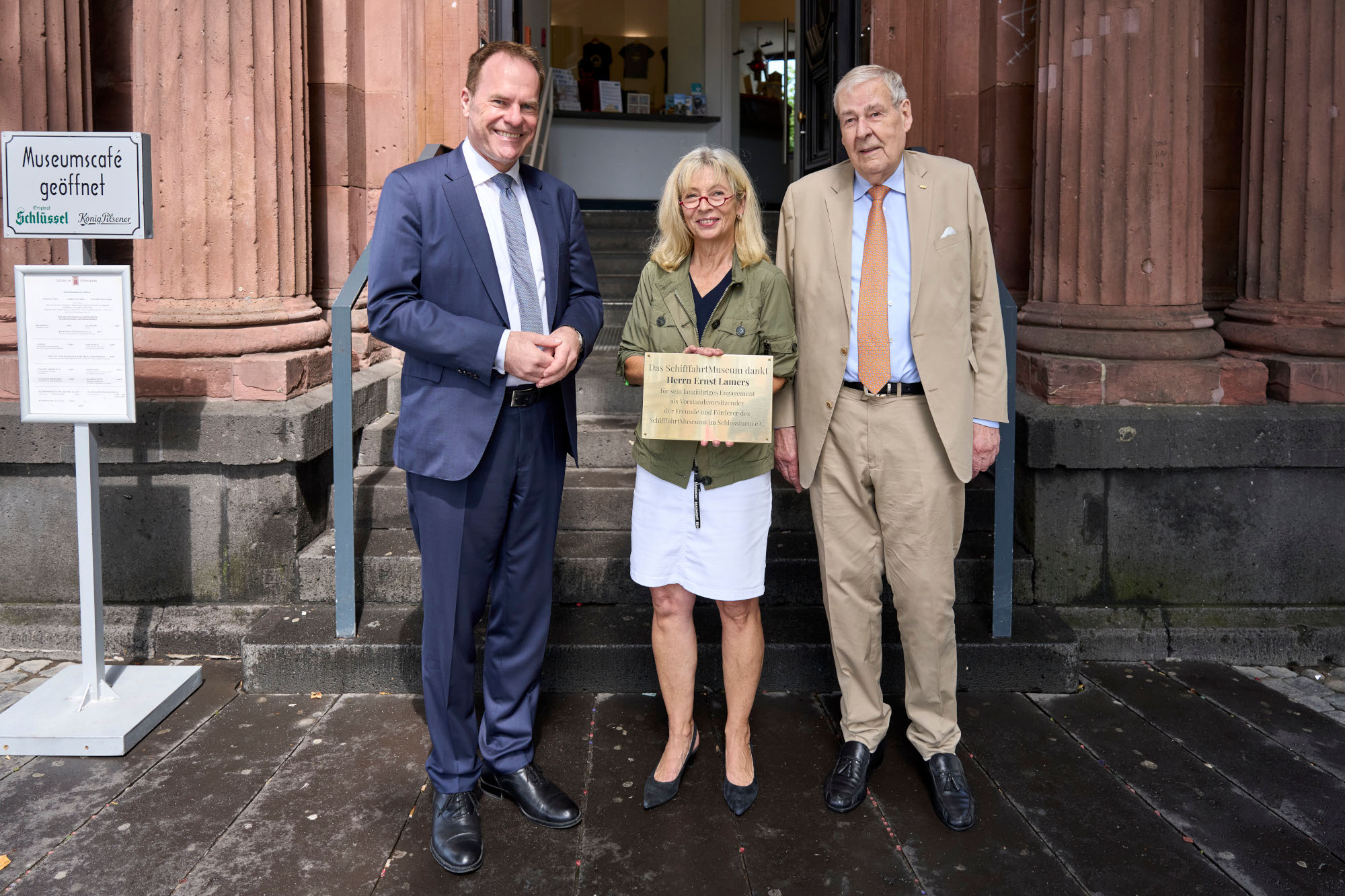 D2C00724_Langer_small OB Dr. Stephan Keller (l.) präsentiert mit Dr. Annette Fimpeler, Leiterin des SchifffahrtMuseums (m.) die Ehrenplakette für Ernst Lamers (r.), ehemaliger Vorsitzender des Freundeskreises vor dem Portal des Schlossturms, © Landeshauptstadt Düsseldorf/Lange